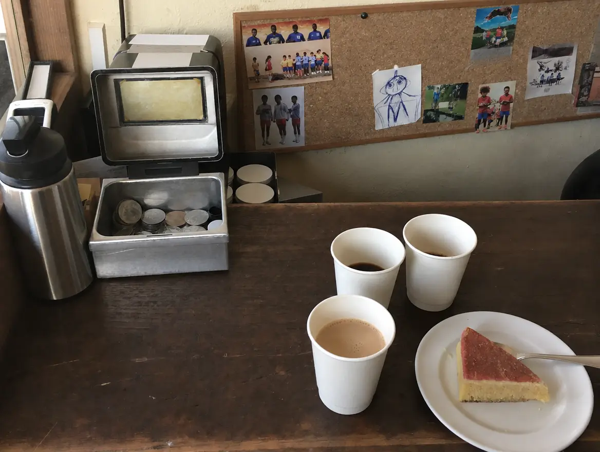 Le comptoir de la buvette avec des cafés, un gâteau maison et une caisse