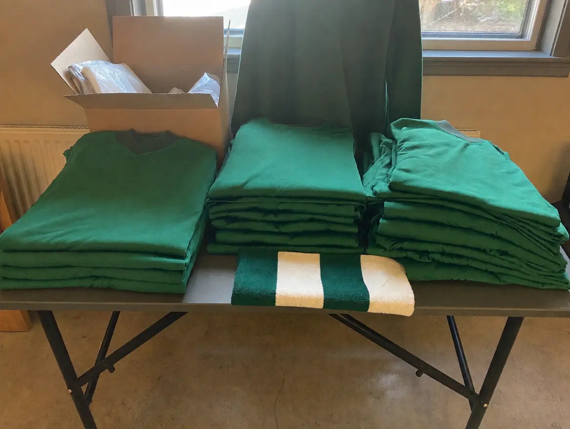 Des maillots verts du club pliés en piles sur une table du club-house